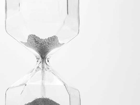 glass sand clock on white with golden balls instead of sand falling Deadline concept that time is ending